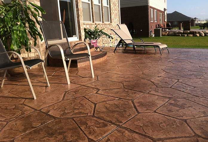 A backyard patio has been stamped and colored to mimic flagstone
